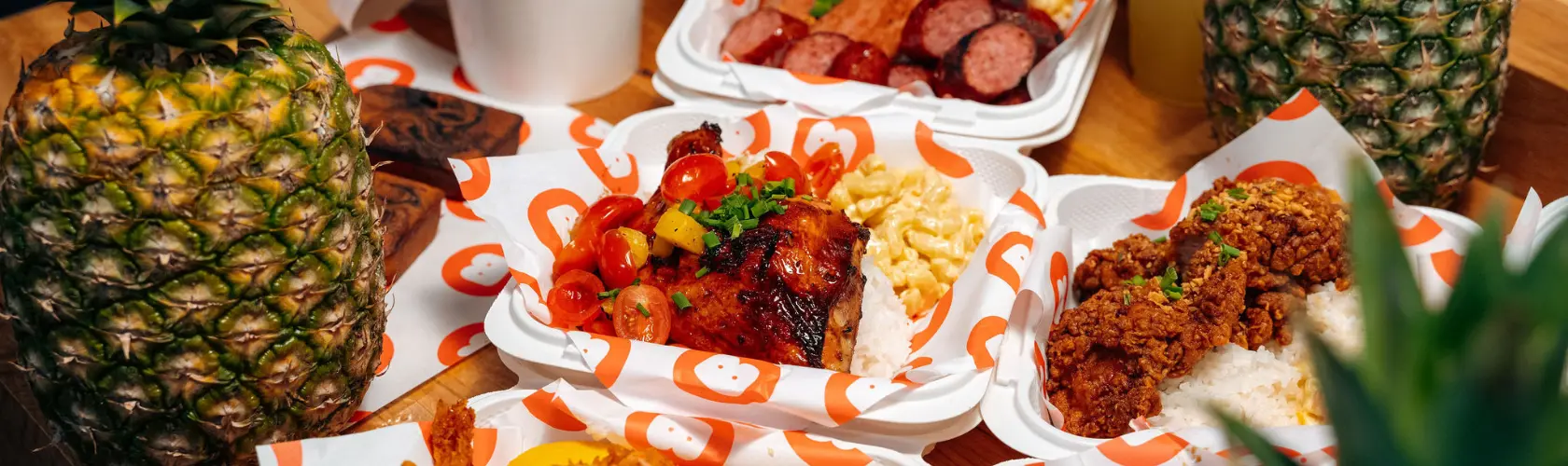 Overhead Hawaiian food trays with chicken, fried sides, rice and pineapple