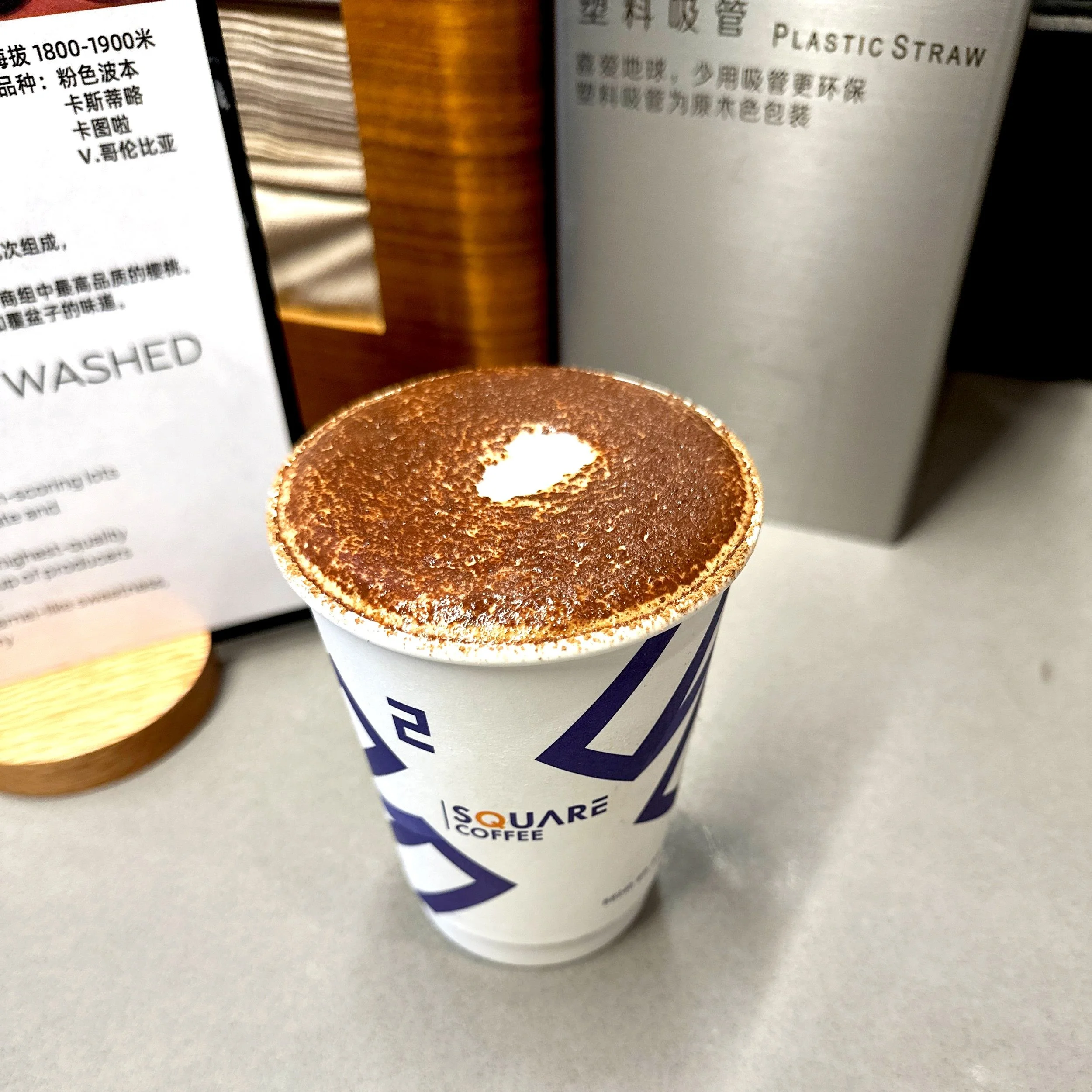 Vienna Coffee 维也纳咖啡 — hot coffee with cinnamon and cocoa dusted foam in a Square Coffee paper cup