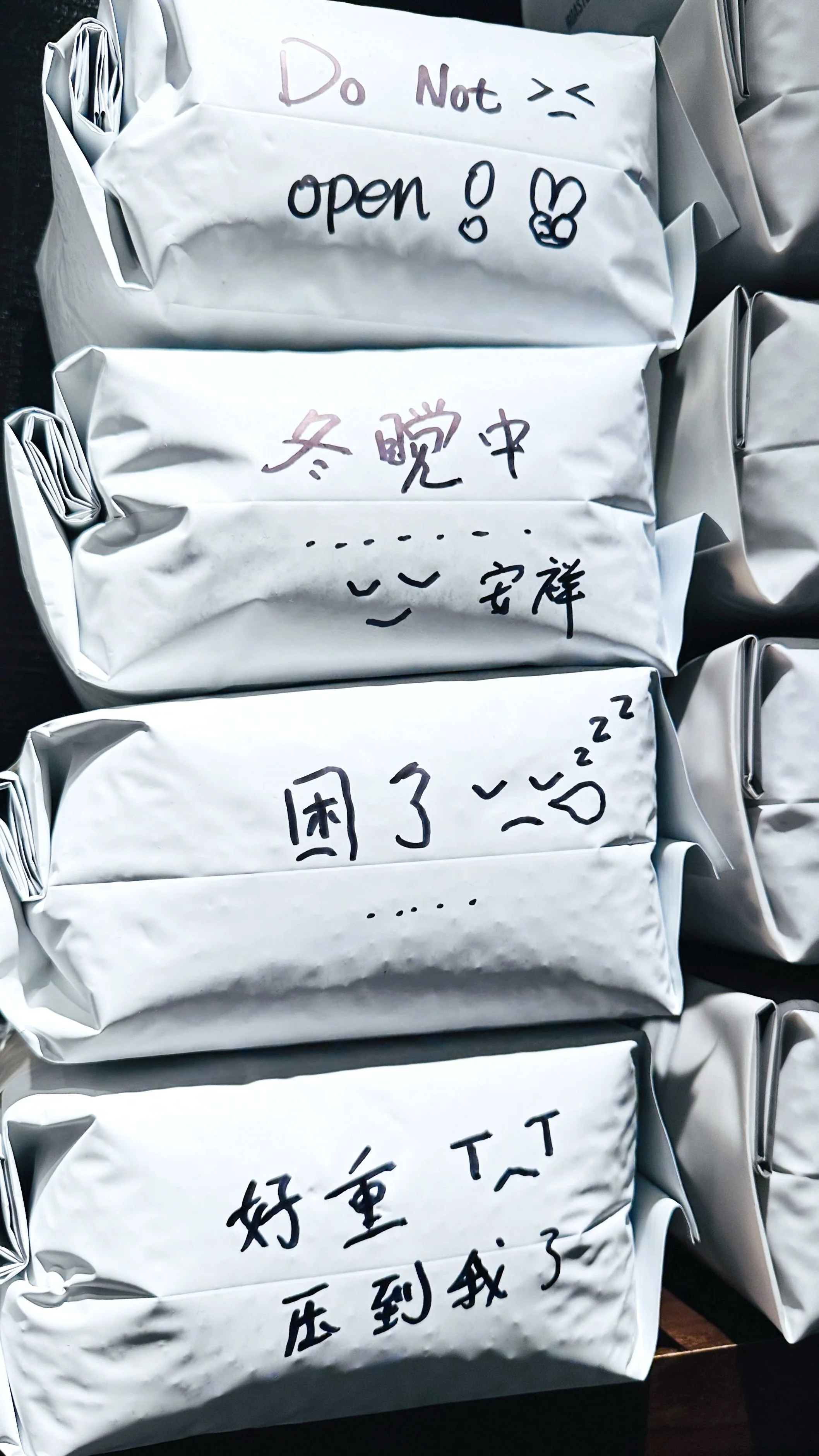 Stacked white coffee bean bags with handwritten Chinese notes and doodles