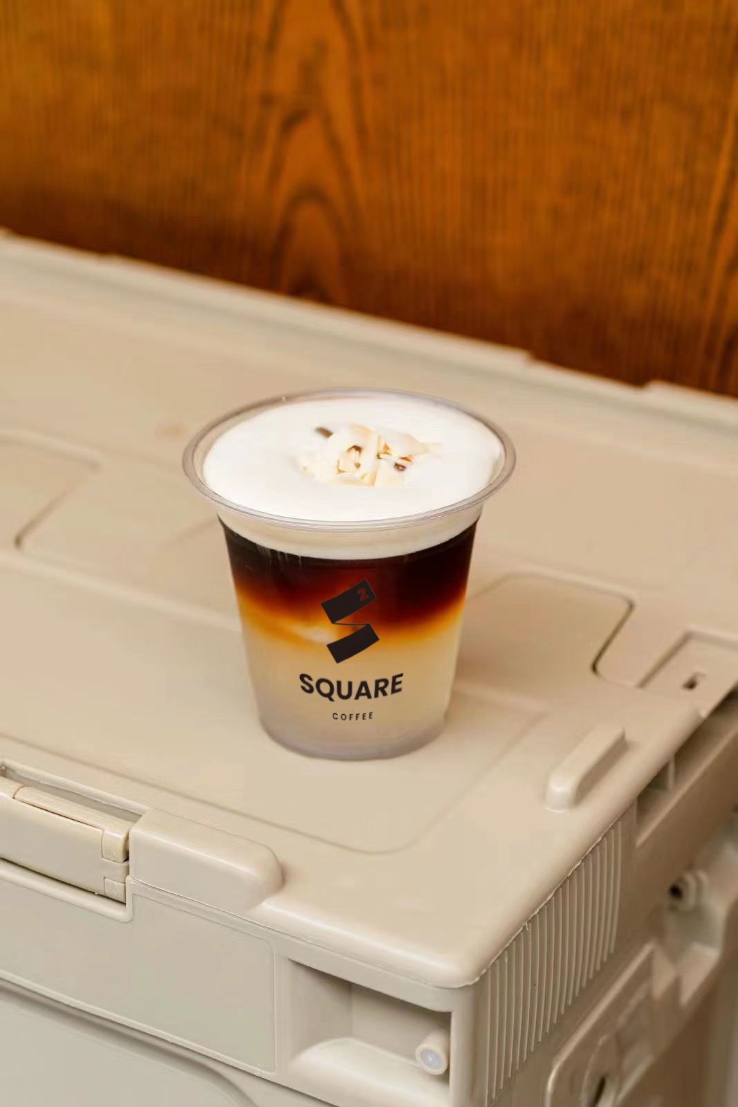 S.H.O — layered iced coffee with thick white foam in a Square Coffee branded clear cup