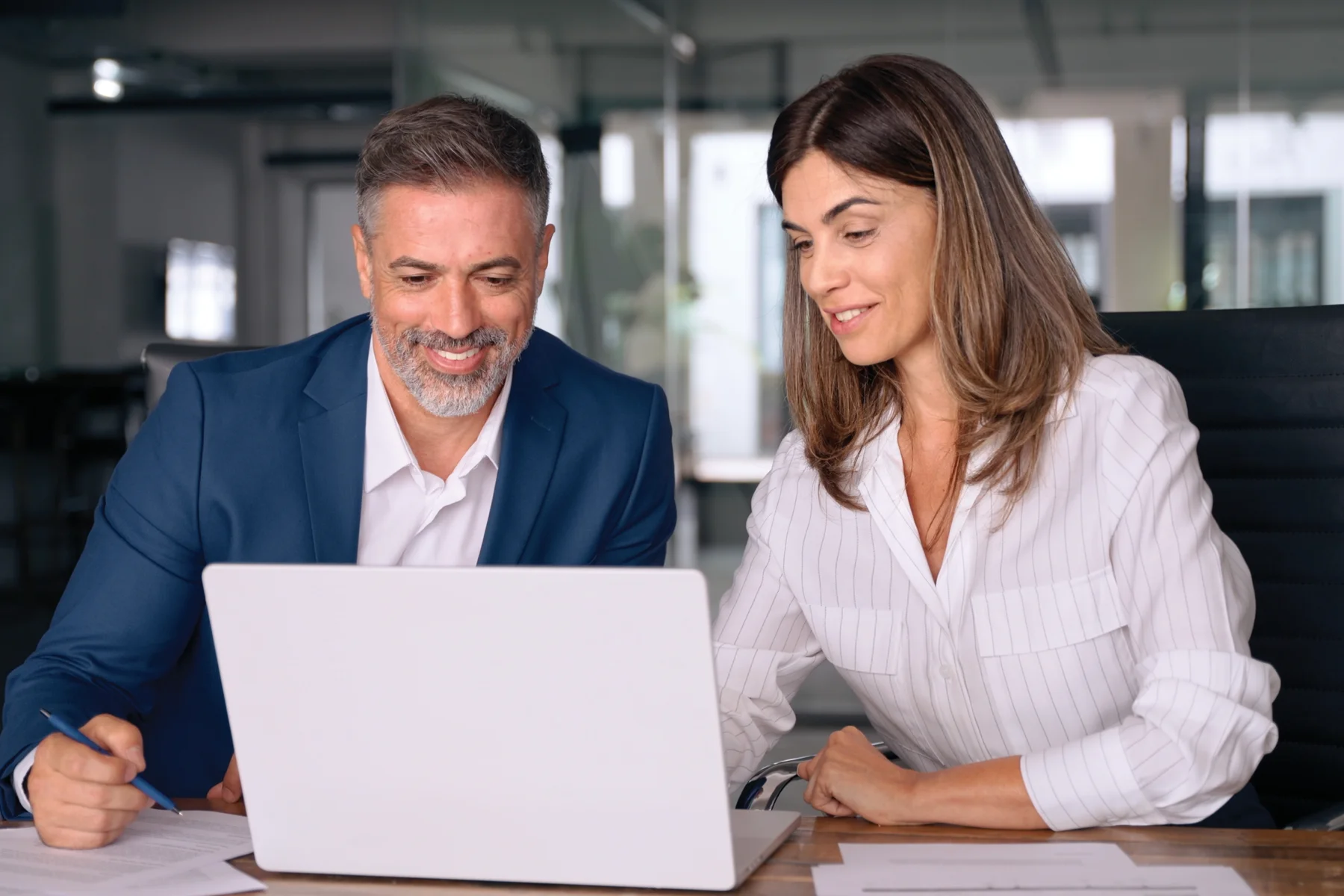 A businessman and businesswoman reviewing work together on a laptop