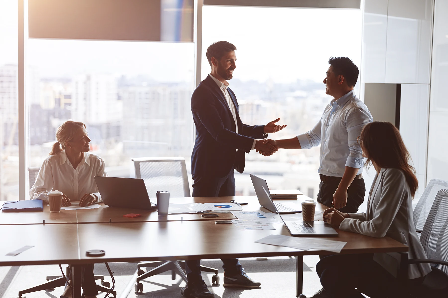 Two businessmen shaking hands across a conference table
