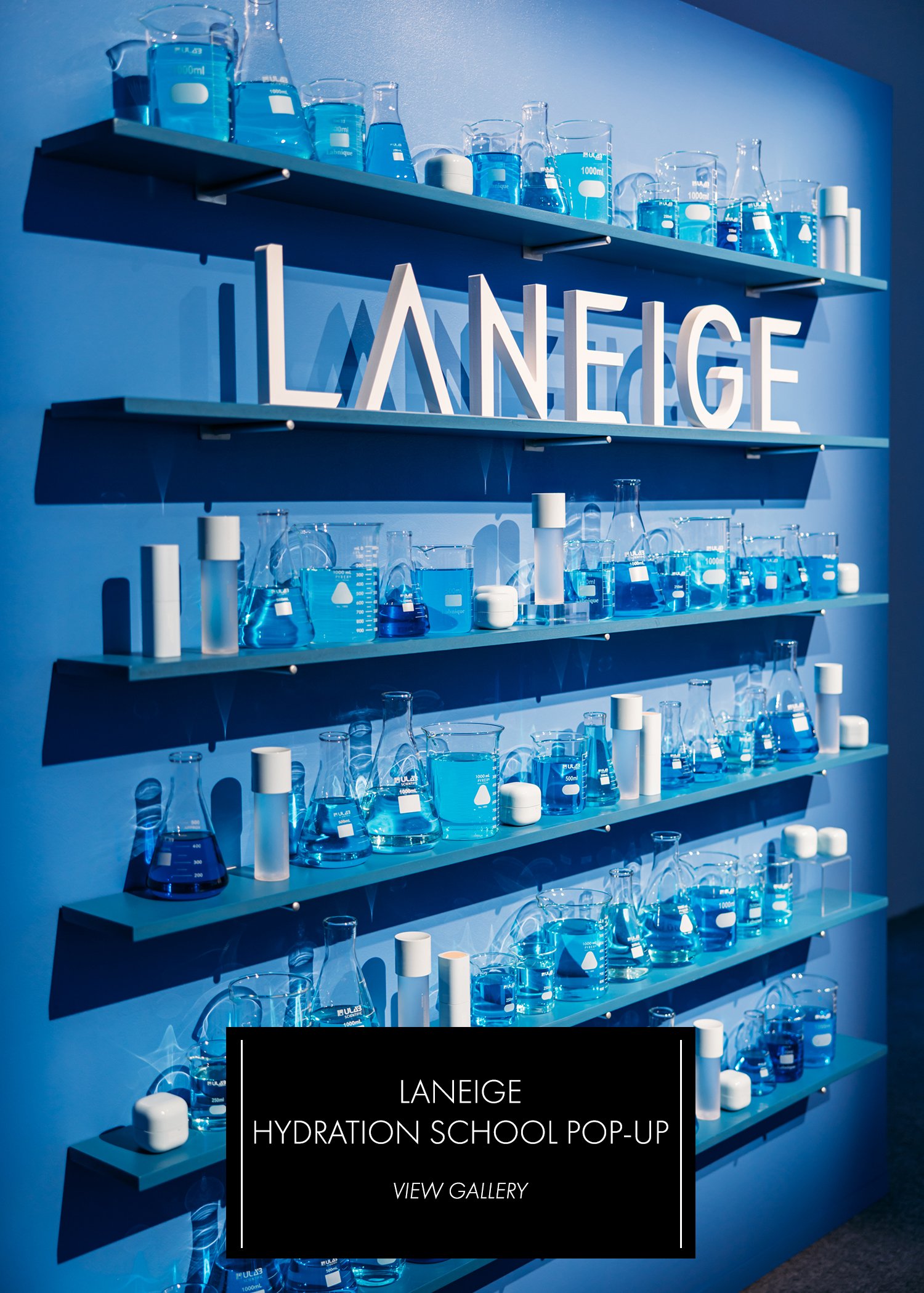 Laneige Hydration School Pop-Up — blue shelving wall with lab glassware and Laneige logo letters