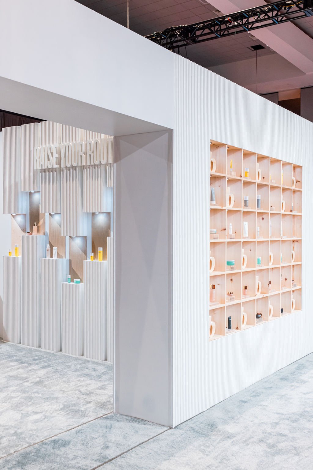 Beautycounter trade show booth interior showing Raise Your Root signage and product display shelves