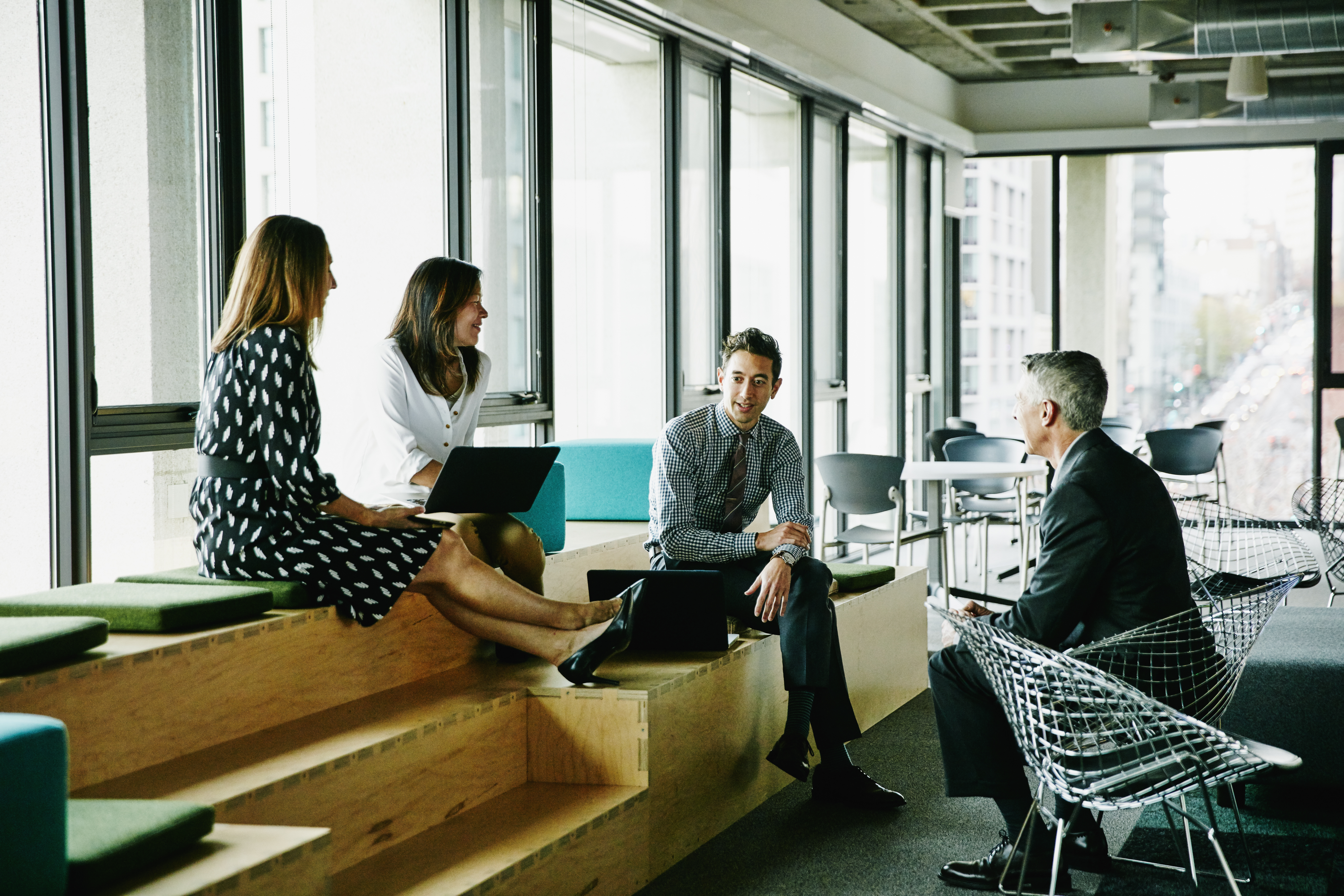 Four business professionals having a discussion in a casual office lounge