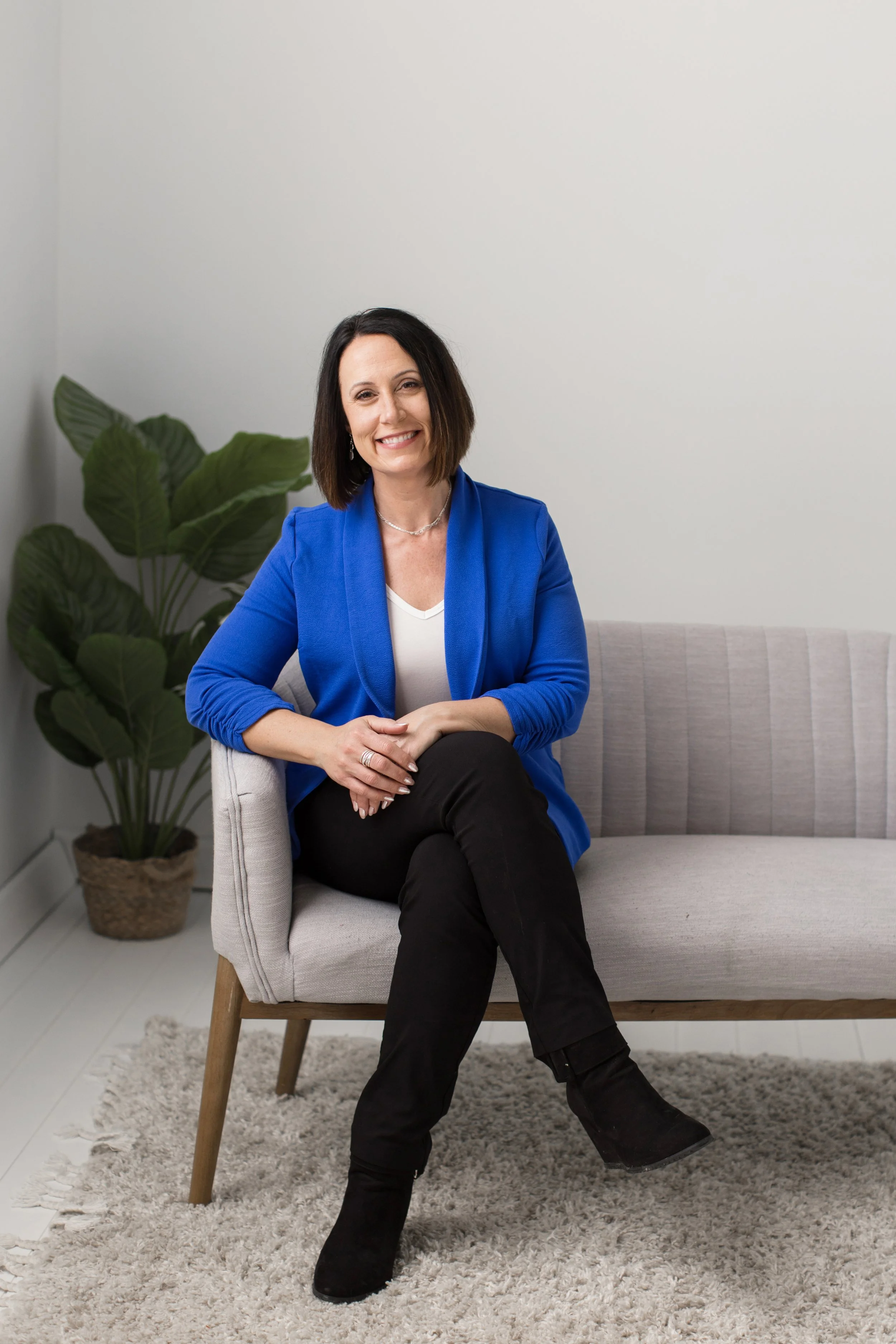 Erin Cambier Ellingson seated on a light grey sofa in a bright blue blazer