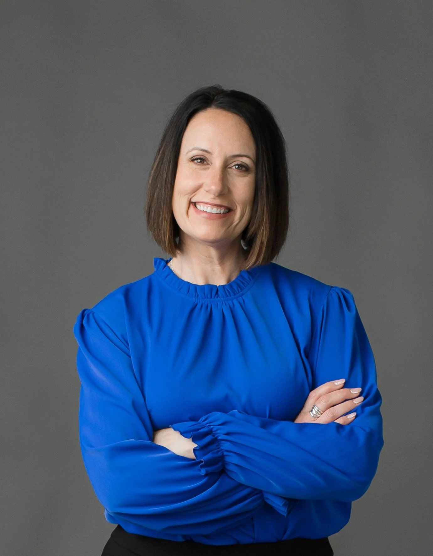 Erin Cambier Ellingson smiling with arms crossed in a blue blouse