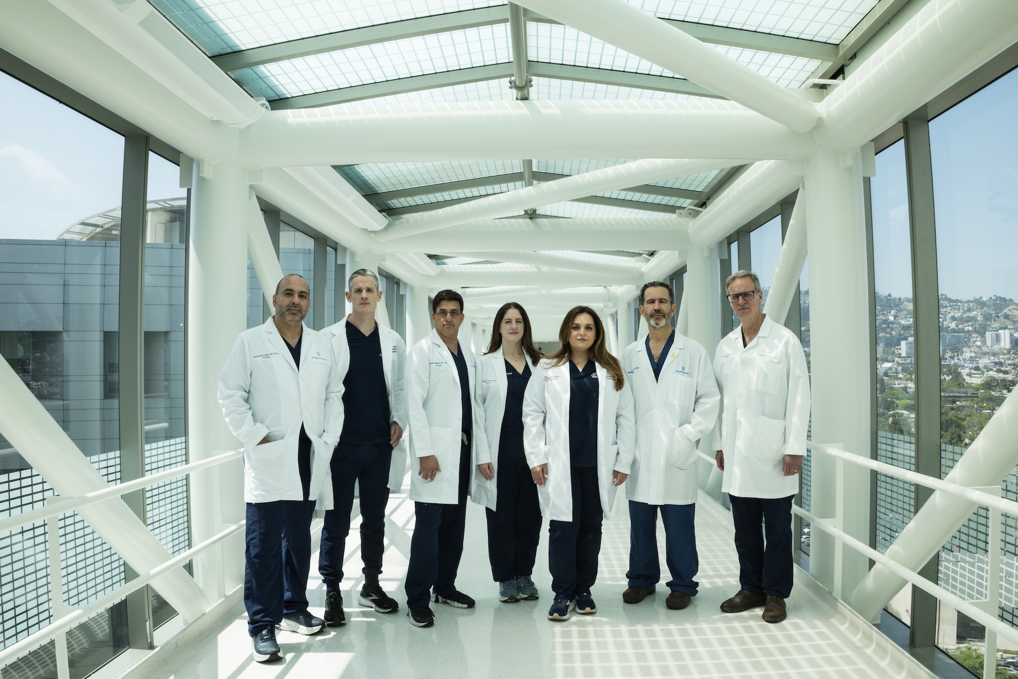 Seven Surgery Group LA surgeons in white coats standing in a glass-walled hospital skybridge
