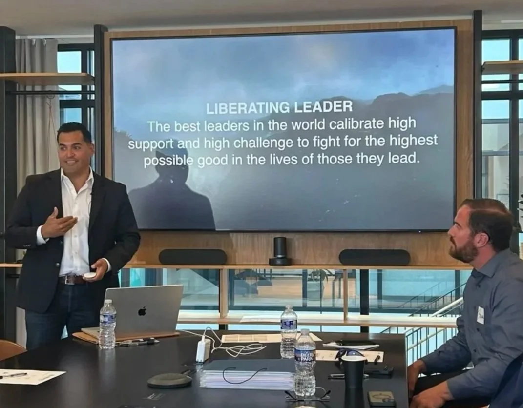 A leadership trainer presenting the Liberating Leader framework to a small group in a conference room