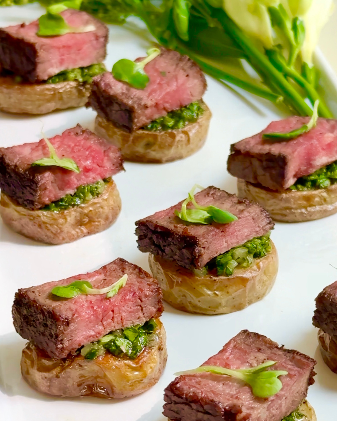 Sliced steak on roasted potato rounds with chimichurri