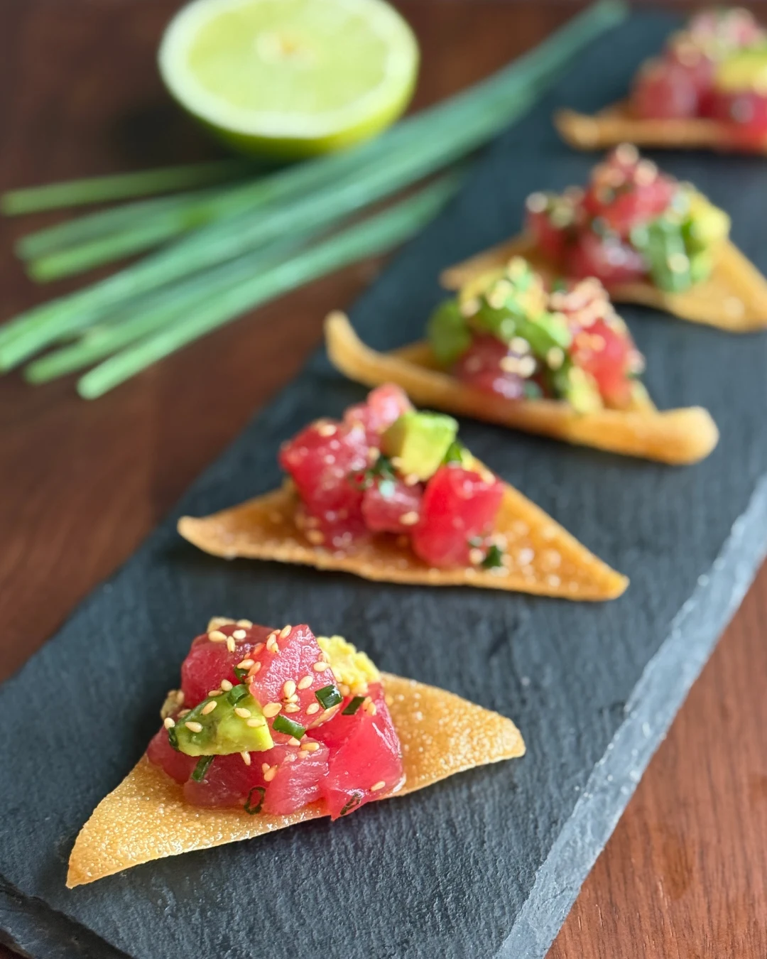 Tuna tartare on crisp wonton with avocado and chive, served on slate