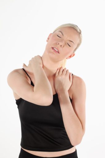 Woman in a black tank top holding her neck and shoulders in pain
