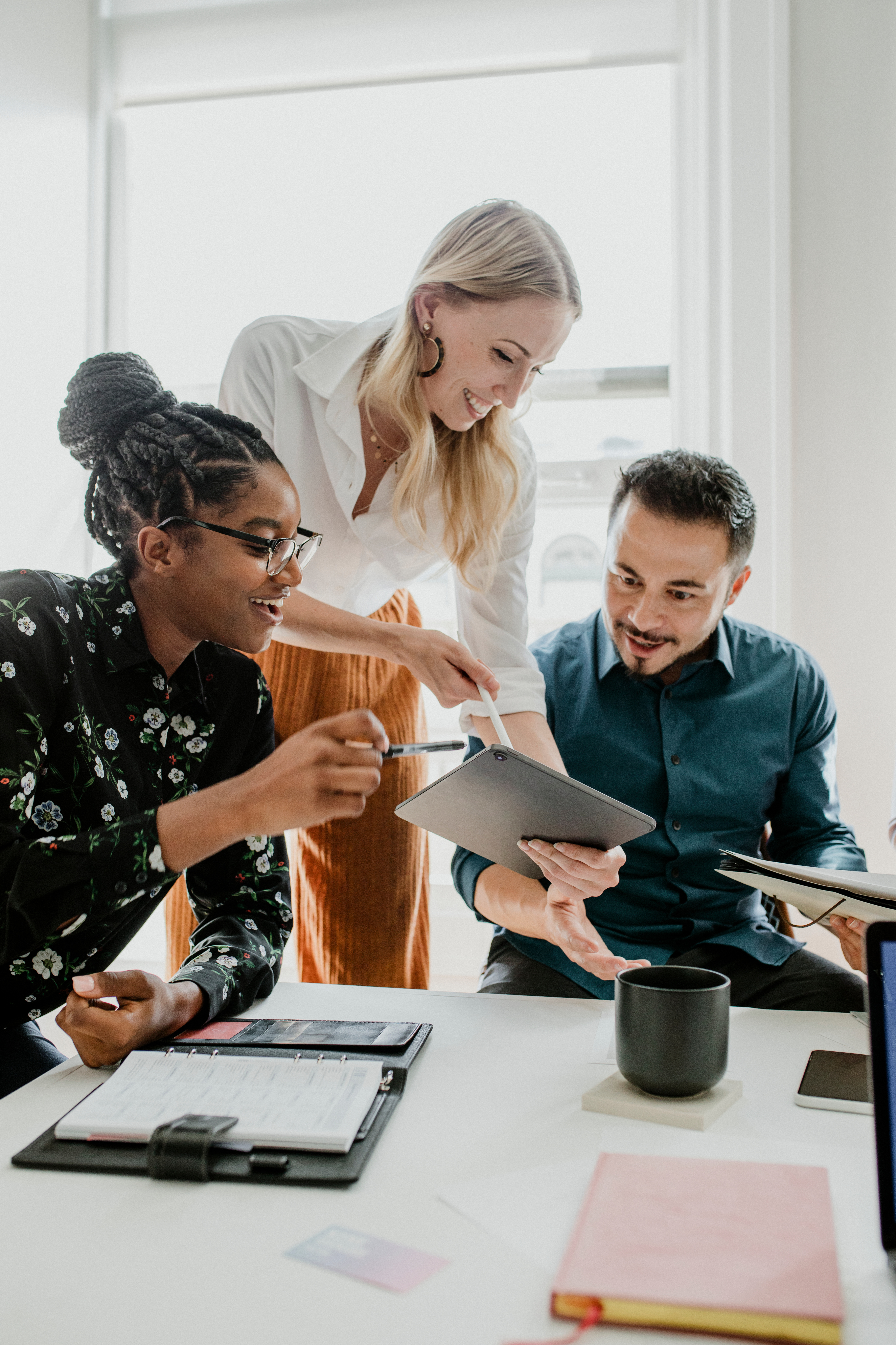 Three diverse colleagues collaborating around a tablet at a white office table