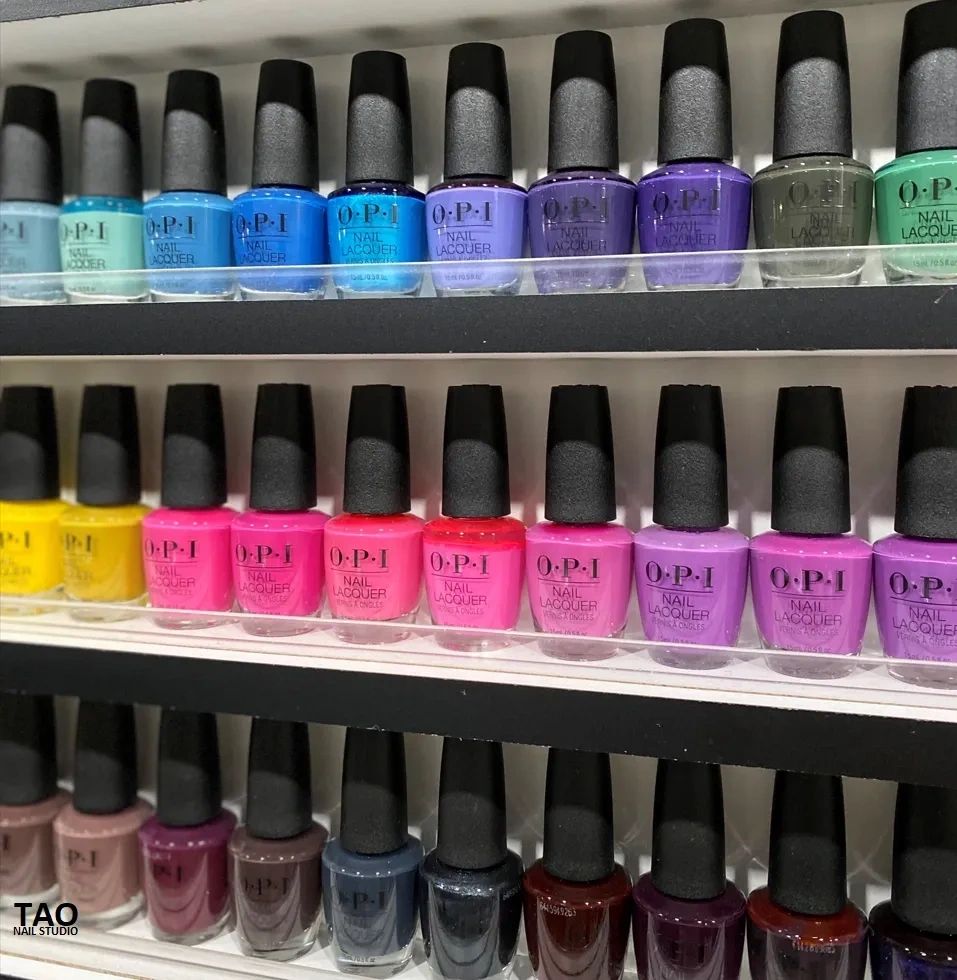 Shelves of colorful OPI nail lacquer bottles arranged in rows by color.