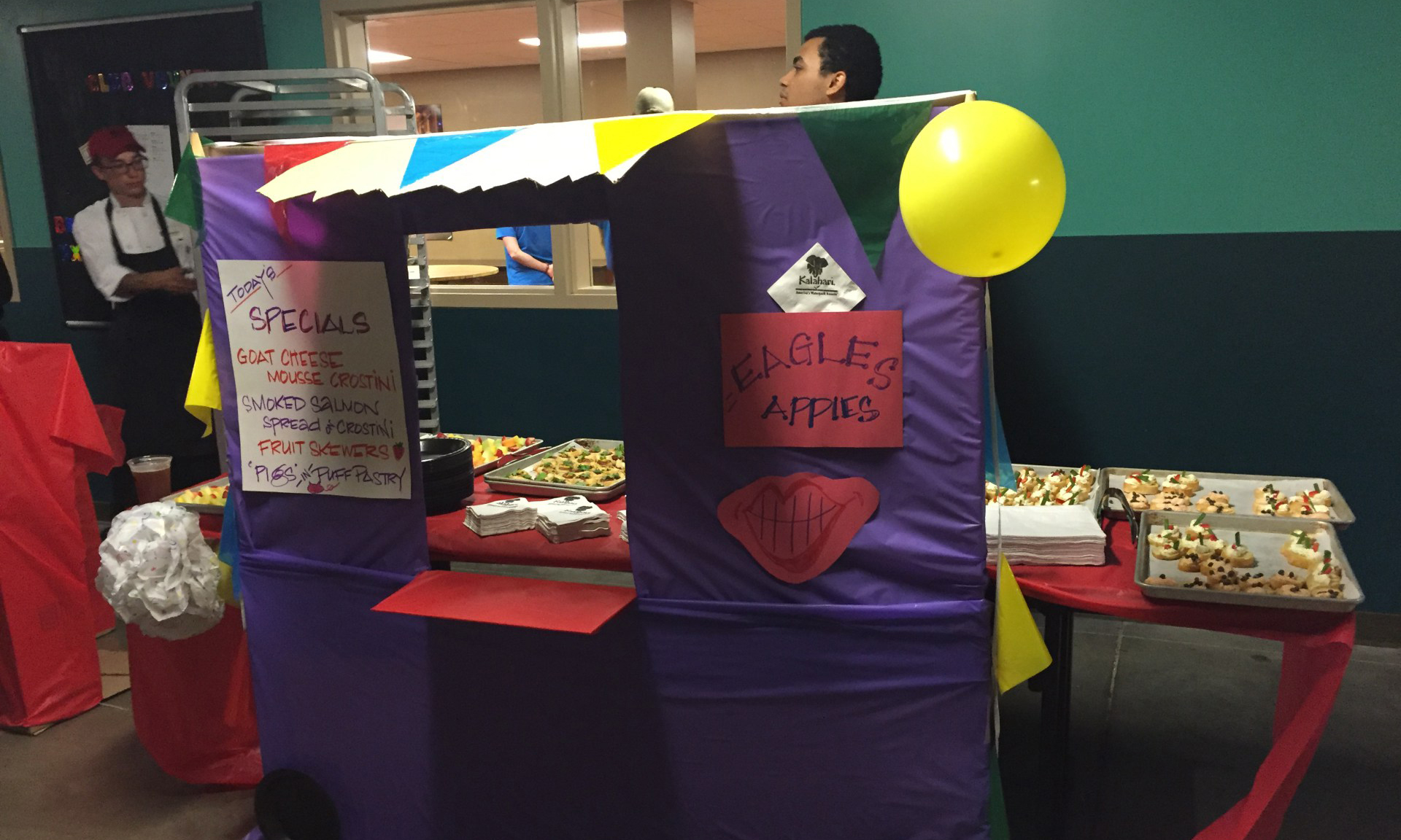 Indoor pop-up food truck team building event with a colorful decorated booth and food trays