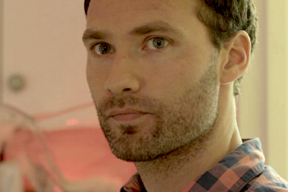 Close-up of a young man with stubble in soft pink light