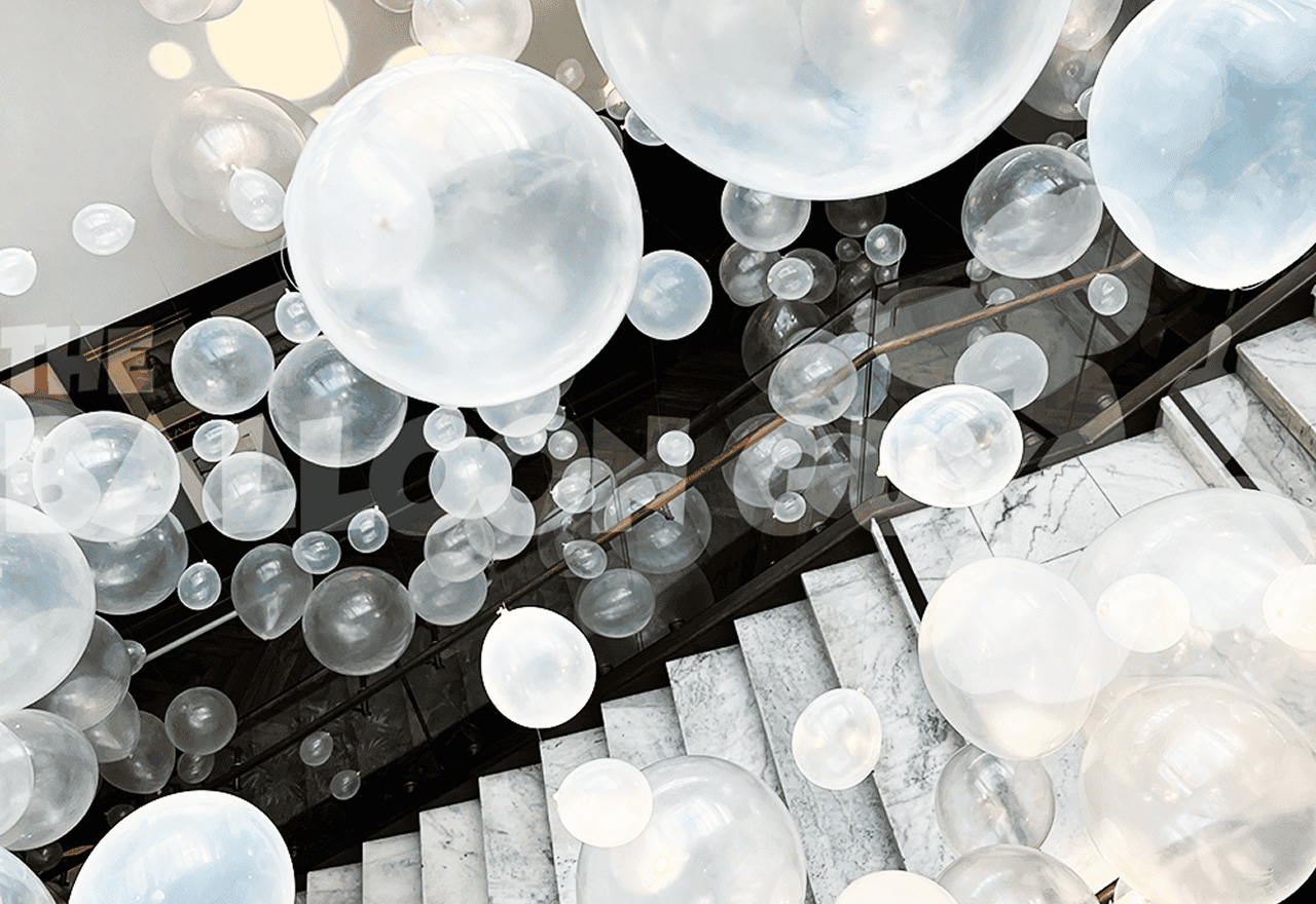 Overhead view of clear and white bubble balloons filling a dark marble stairwell