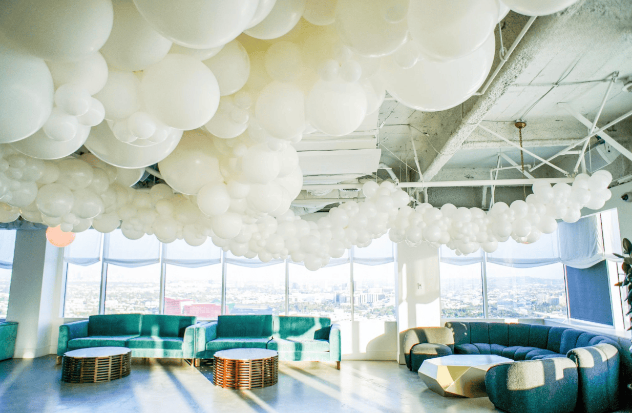 Wide interior of Soho House LA with a white cloud balloon ceiling and teal sofas