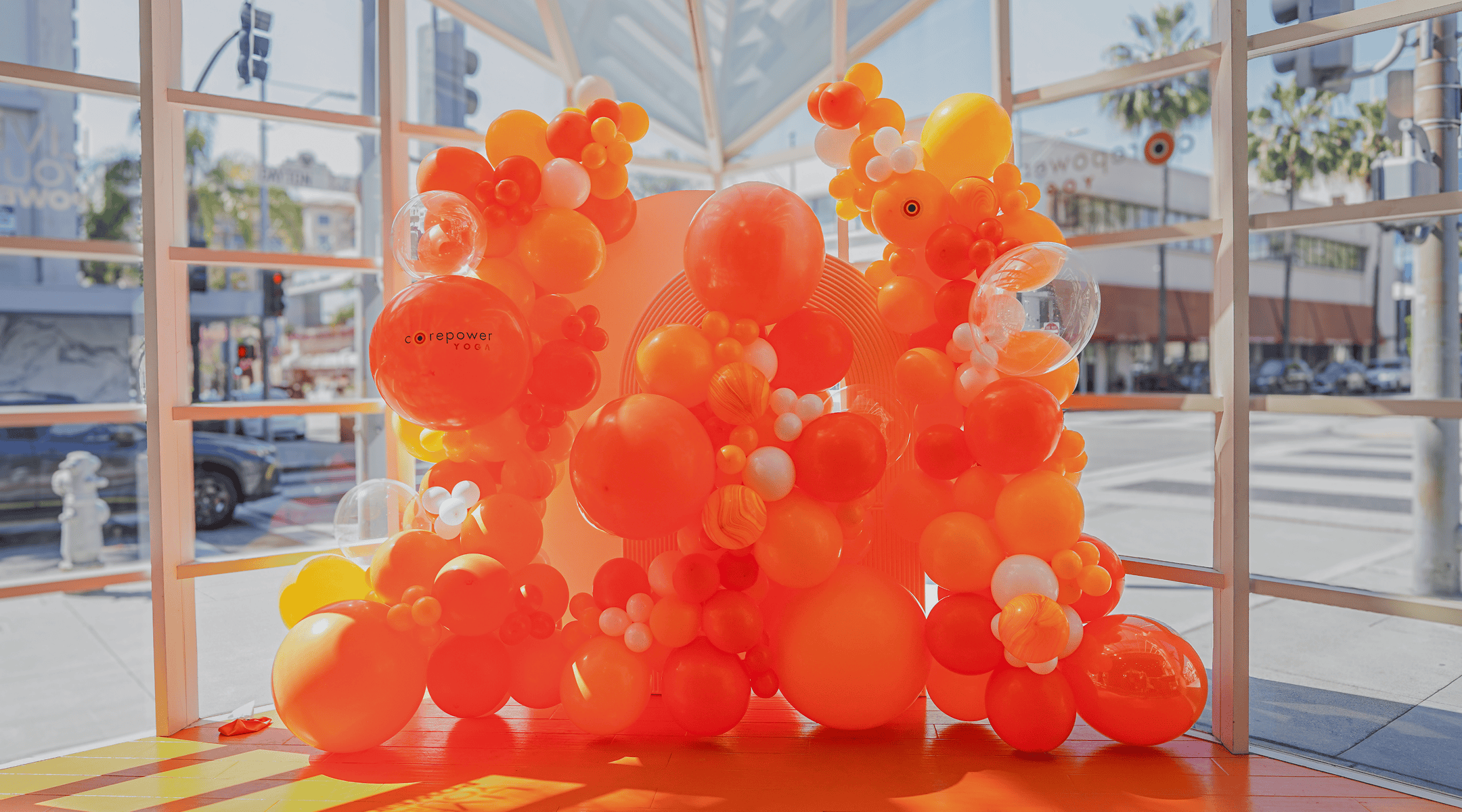 Orange and yellow balloon installation inside a glass-walled CorePower Yoga storefront