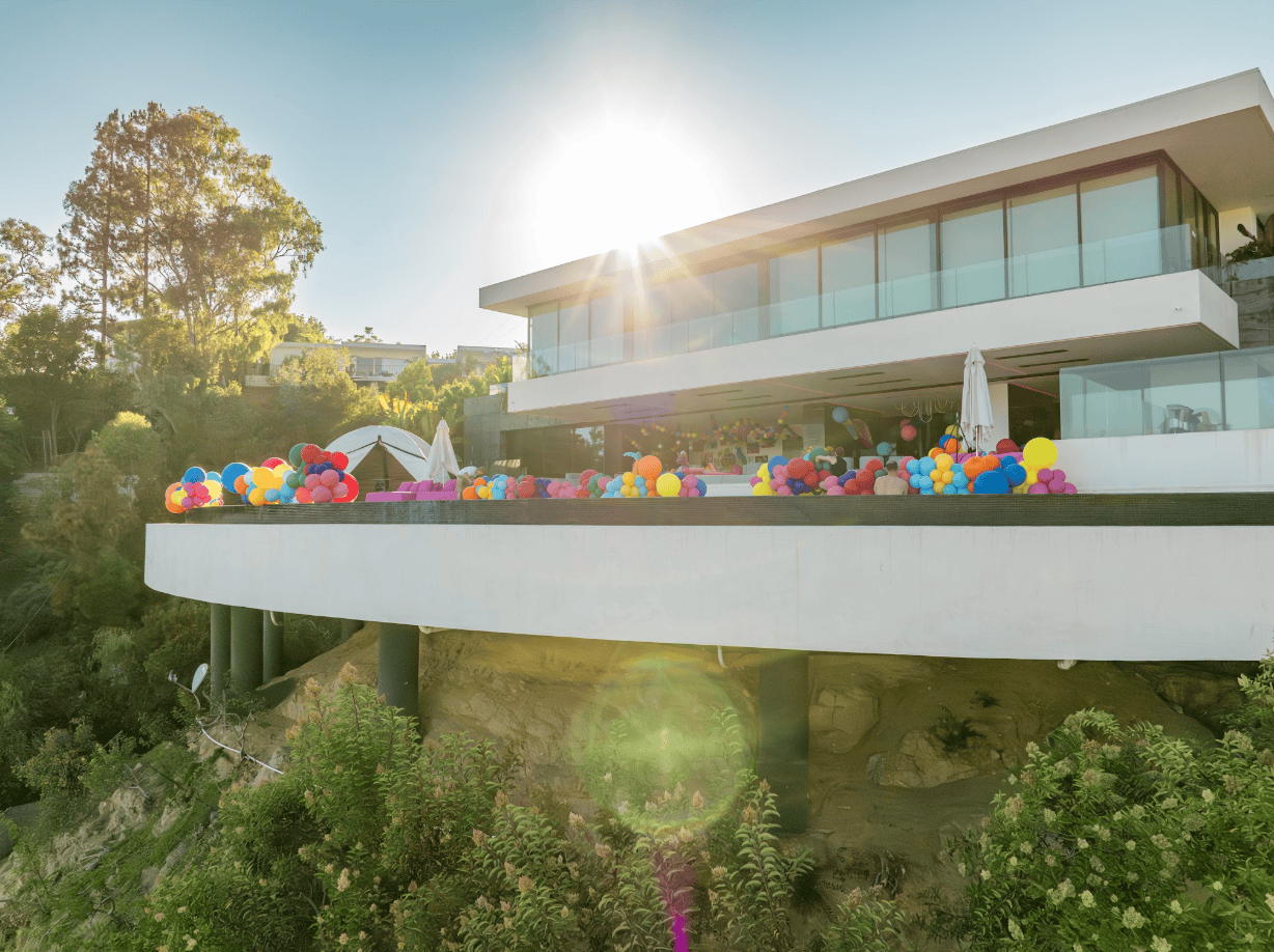 Hillside mansion balcony filled with colorful balloon clusters for a private party