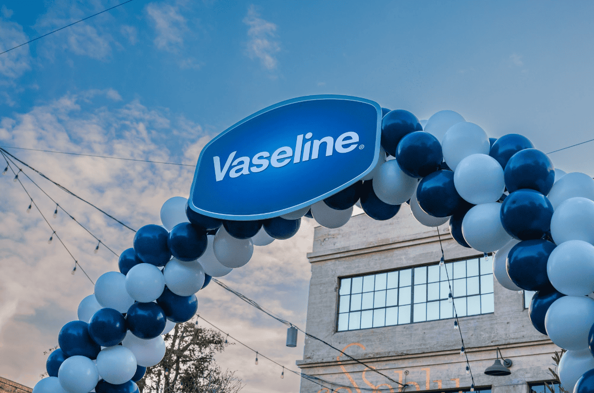 Outdoor navy and white balloon arch with a large Vaseline branded sign at the top