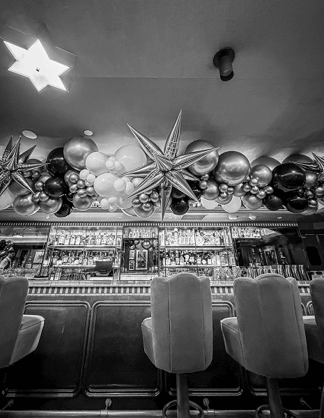Black and white bar interior with a chrome and black balloon garland and starburst foils