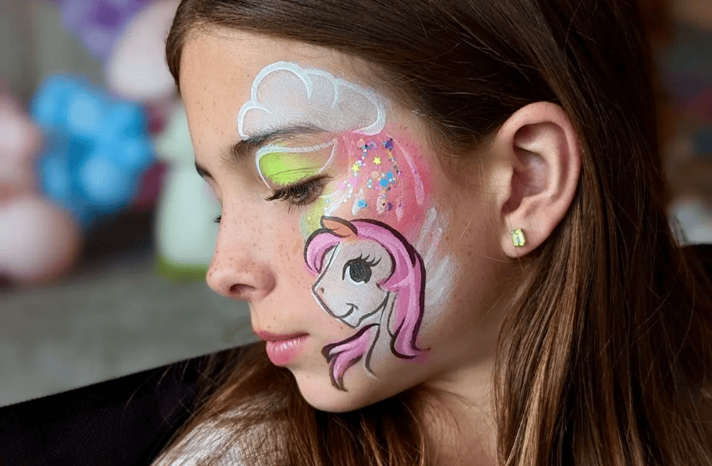 Young girl with a unicorn design painted on her cheek at a party
