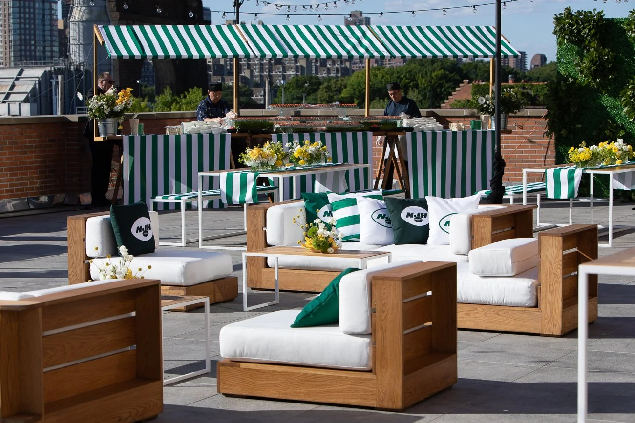 Rooftop terrace set for a NY Jets themed event with green and white striped canopy and lounge furniture