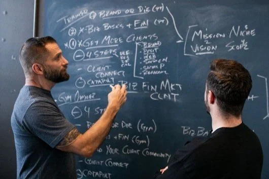Billy Polson mapping financials on a chalkboard while a client watches