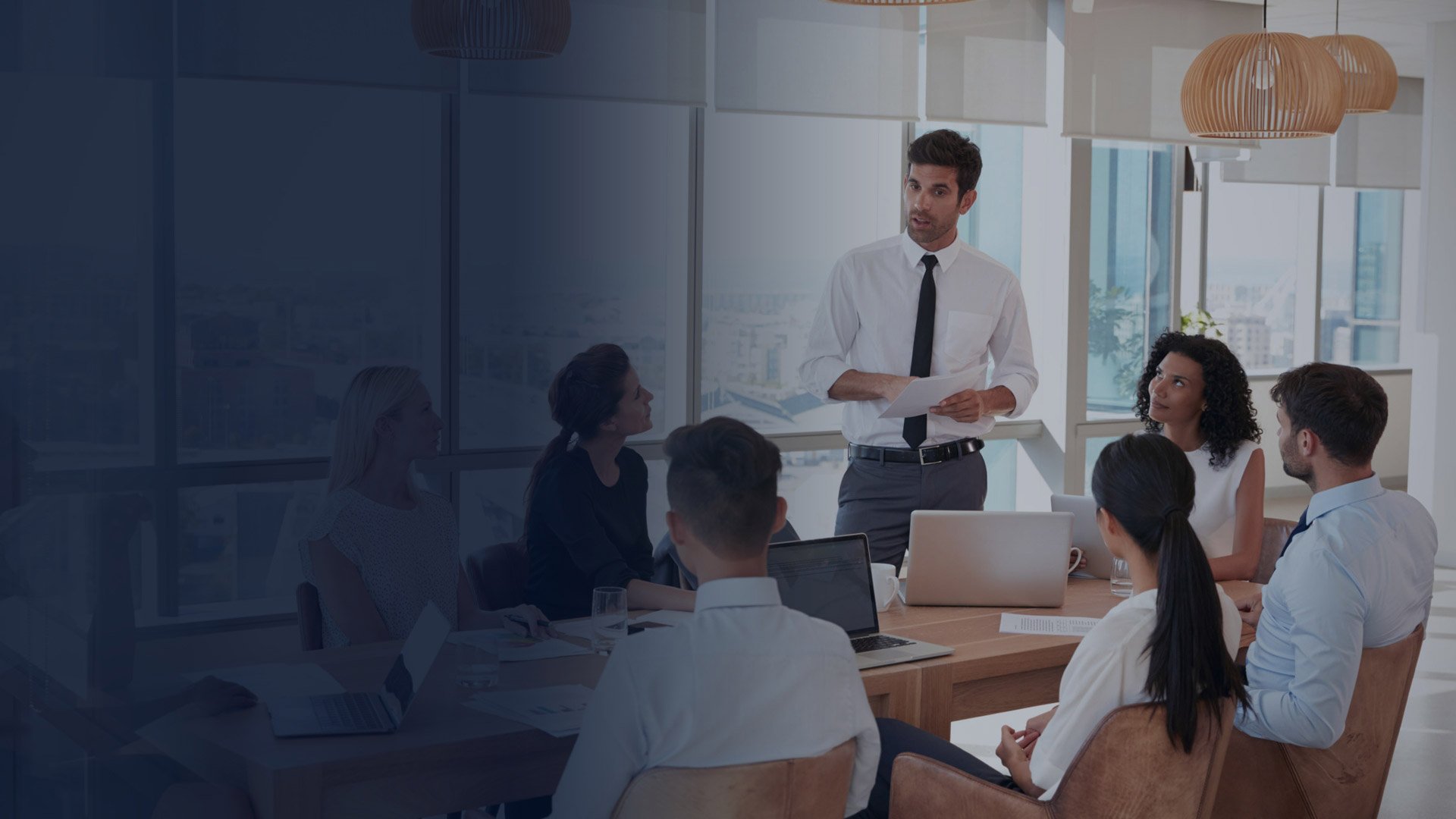 A professional speaking with a seated group of colleagues in a bright modern conference room