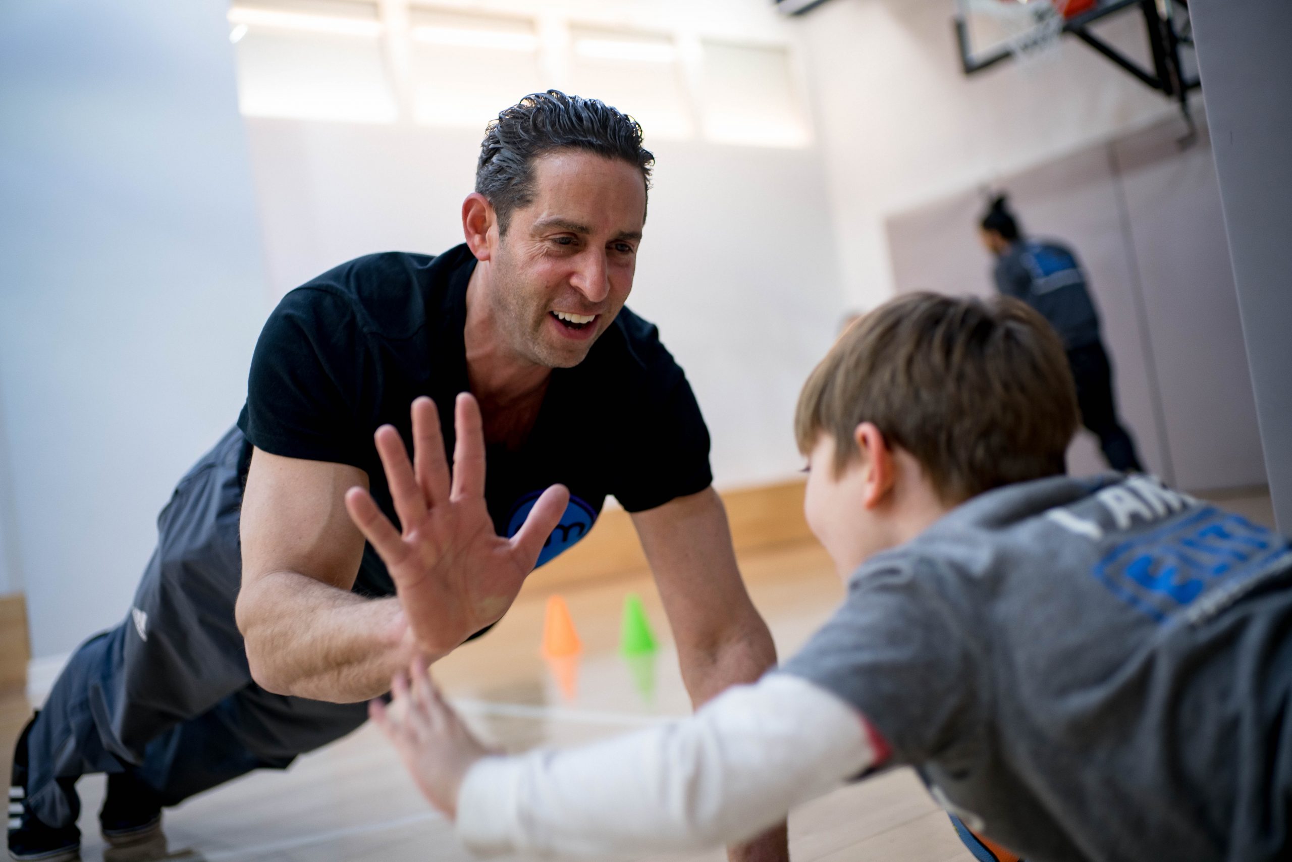 Elite Method coach giving a high-five to a young child on an indoor basketball court