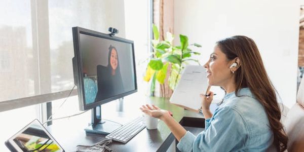 Woman on a video call at her desk, smiling with documents