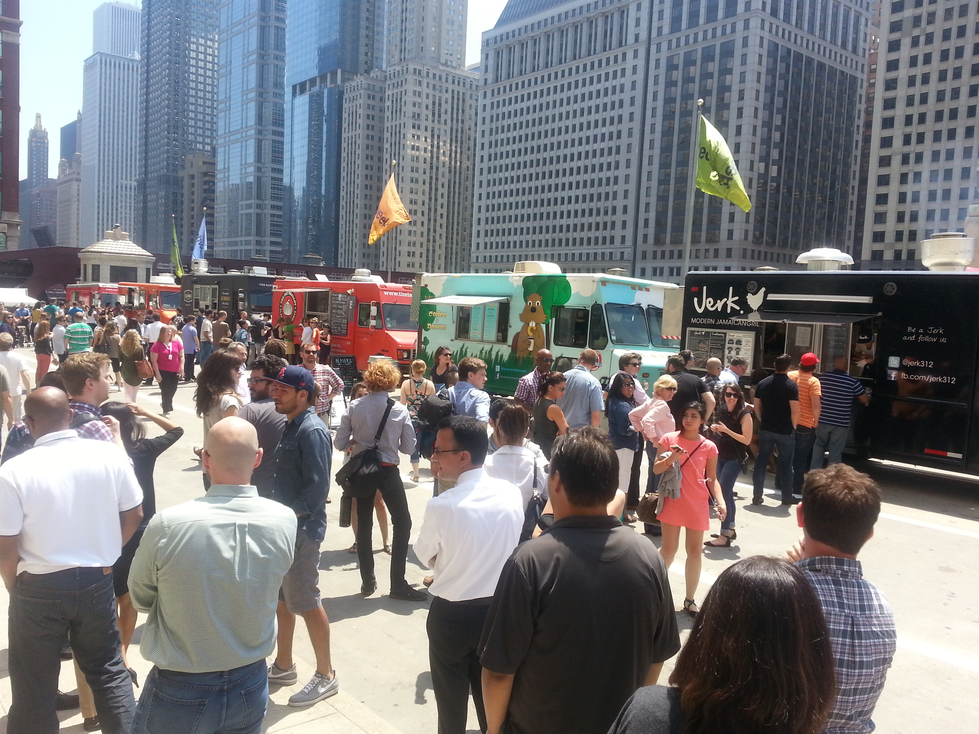 Large crowd of people at an outdoor food truck festival in downtown Chicago with multiple food trucks and city skyline