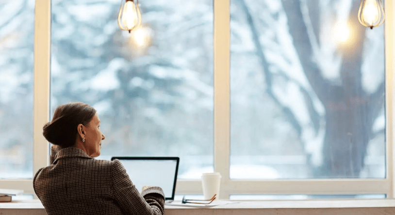 Woman at a desk looking out a snowy window