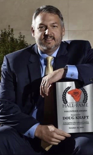 Doug Kraft holding a Hall of Fame Volunteer Award plaque