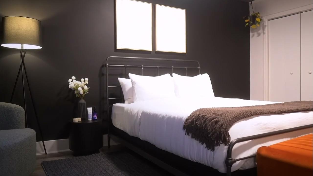 A dark-walled bedroom suite with white linens and an orange accent at The Rest Spot