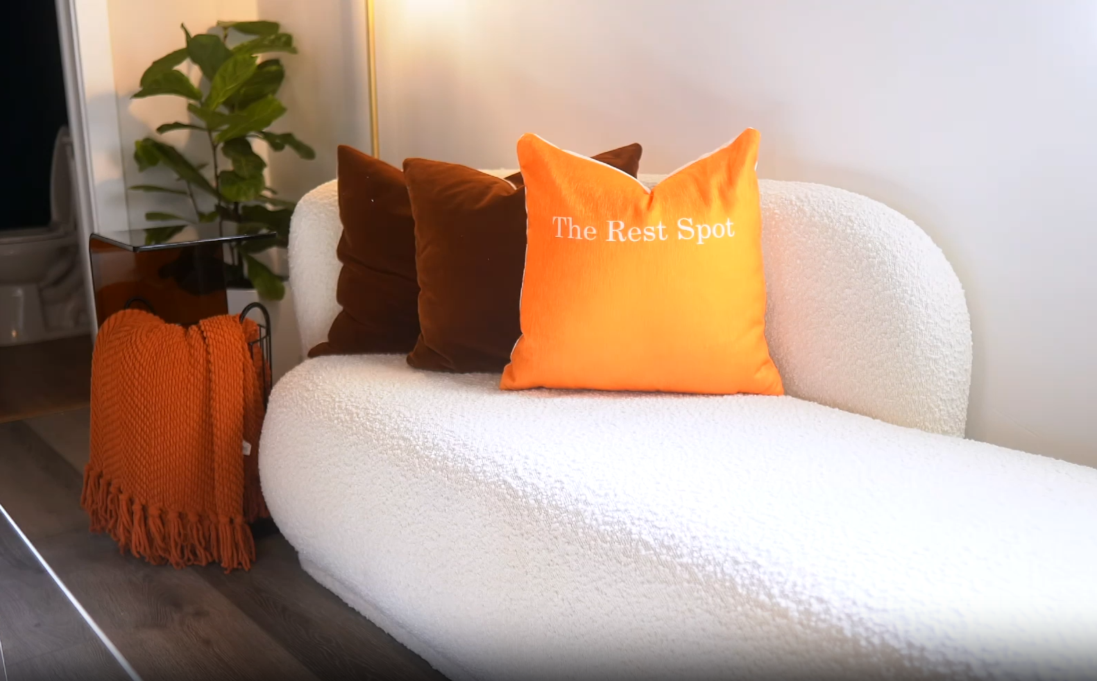 White bouclé sofa with a branded orange The Rest Spot pillow in the Respite Lounge