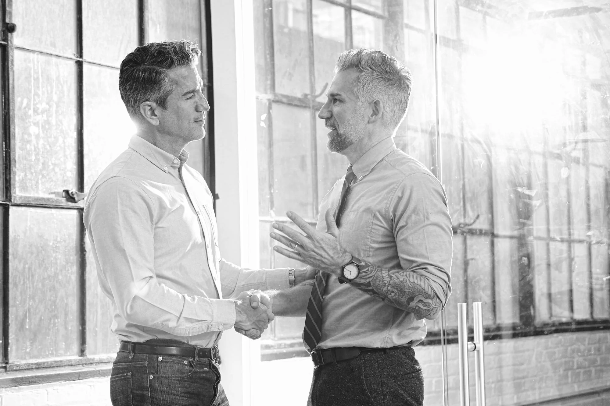 Two professionals shaking hands in a bright industrial New York loft