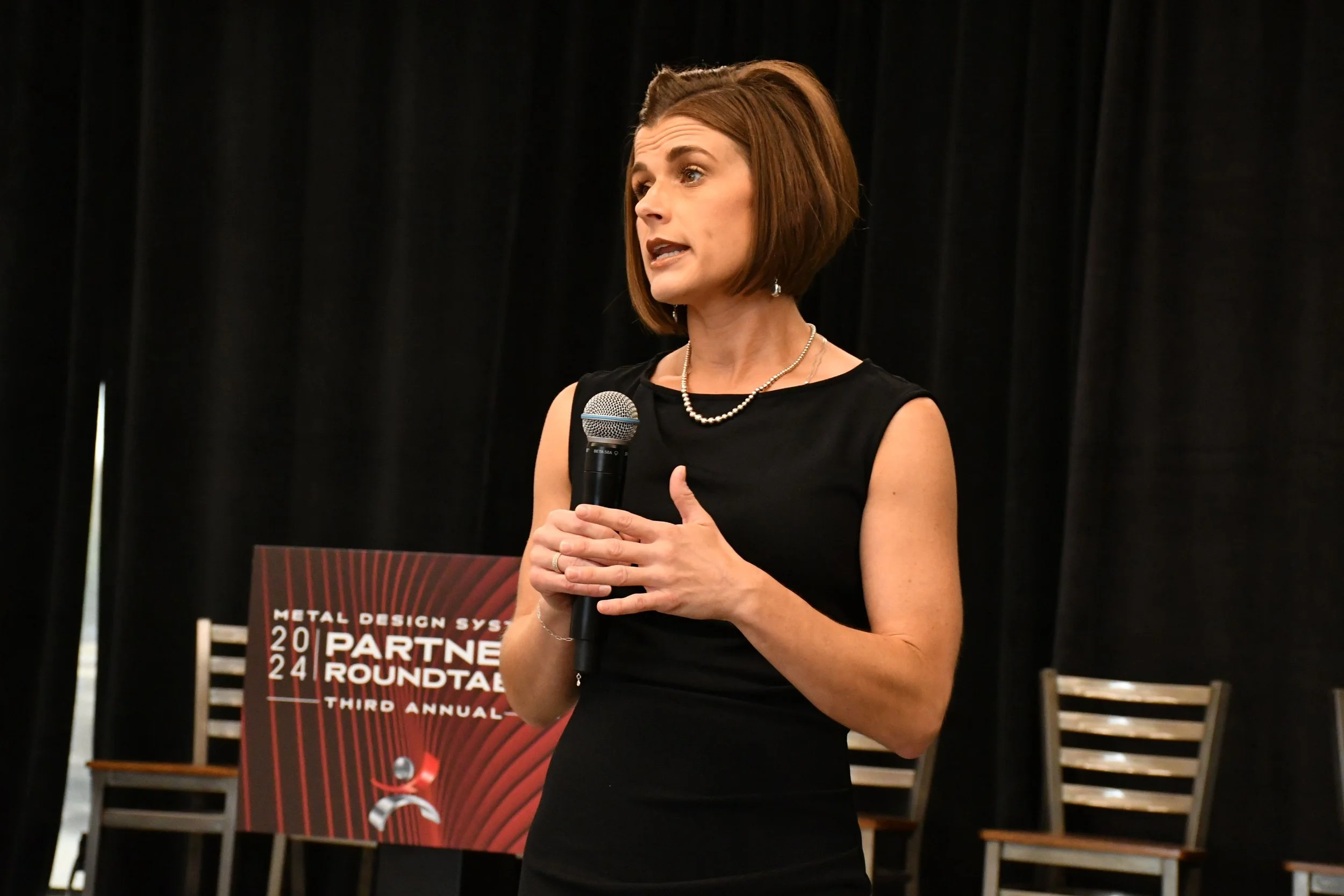 Andrea Singsaas presenting a keynote on stage at a corporate partner roundtable