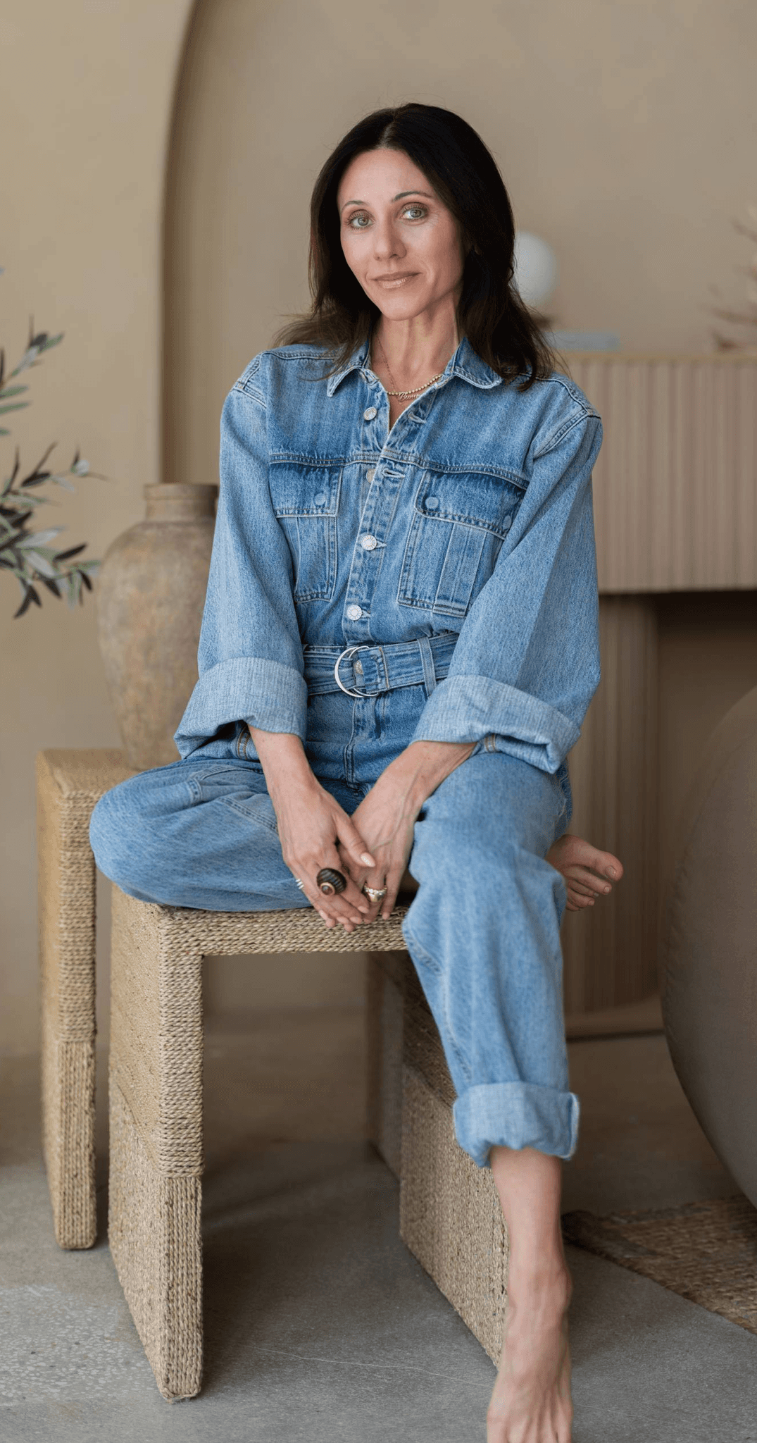 Amber Berger seated in denim in a warm, sunlit plaster interior