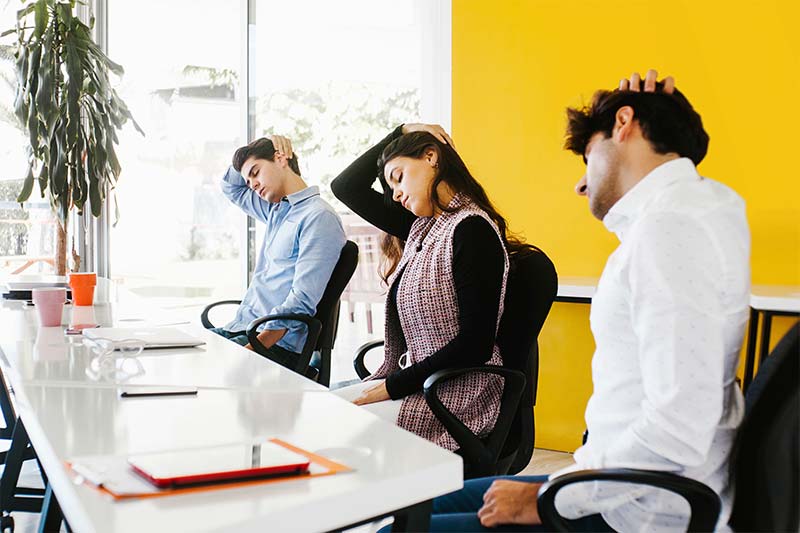 Office workers stretching at a conference table