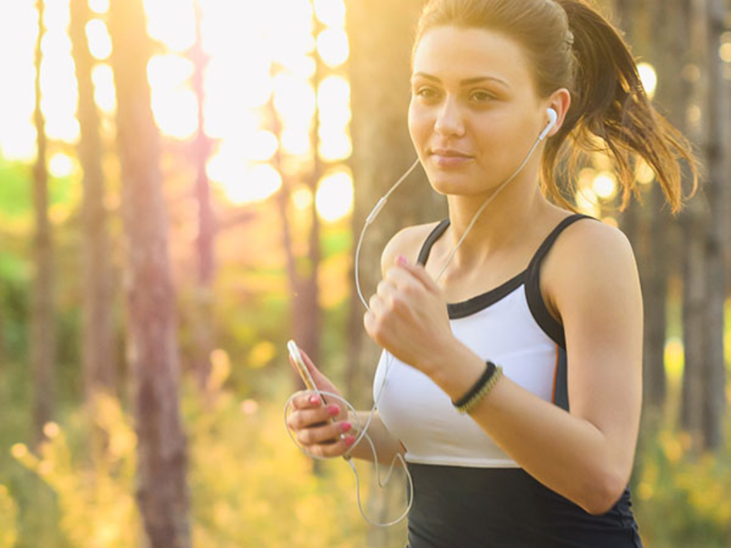 Woman jogging through a sunny forest