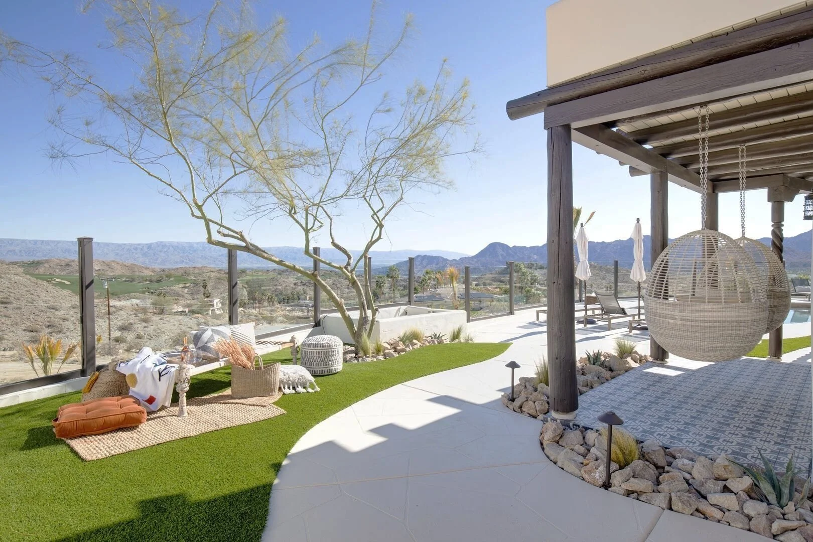 Desert retreat patio with a hanging wicker chair, pergola and mountain view