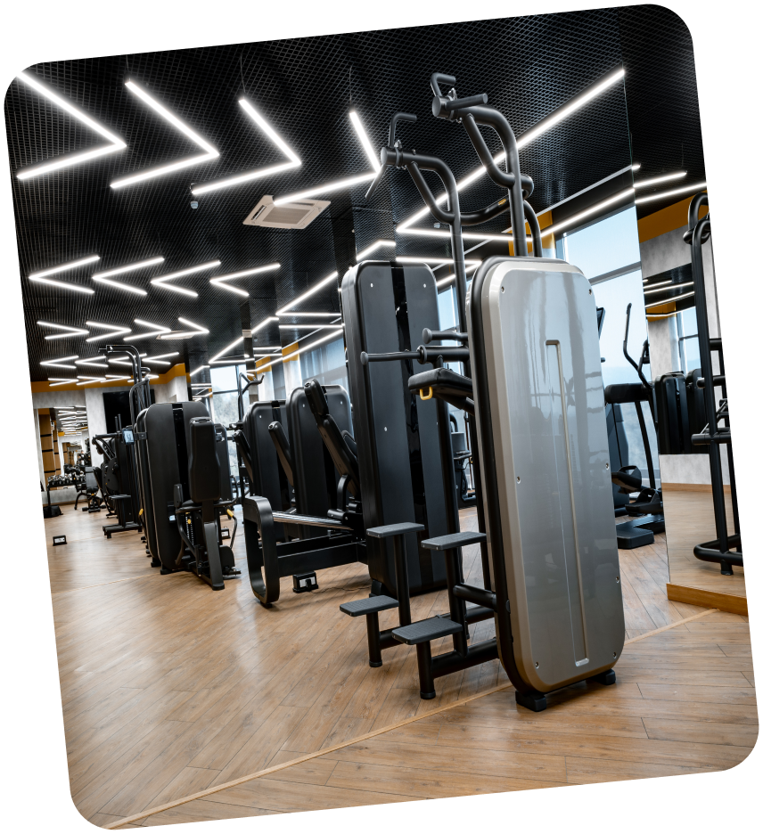 Interior of a modern gym with rows of weight machines and zigzag LED ceiling lights