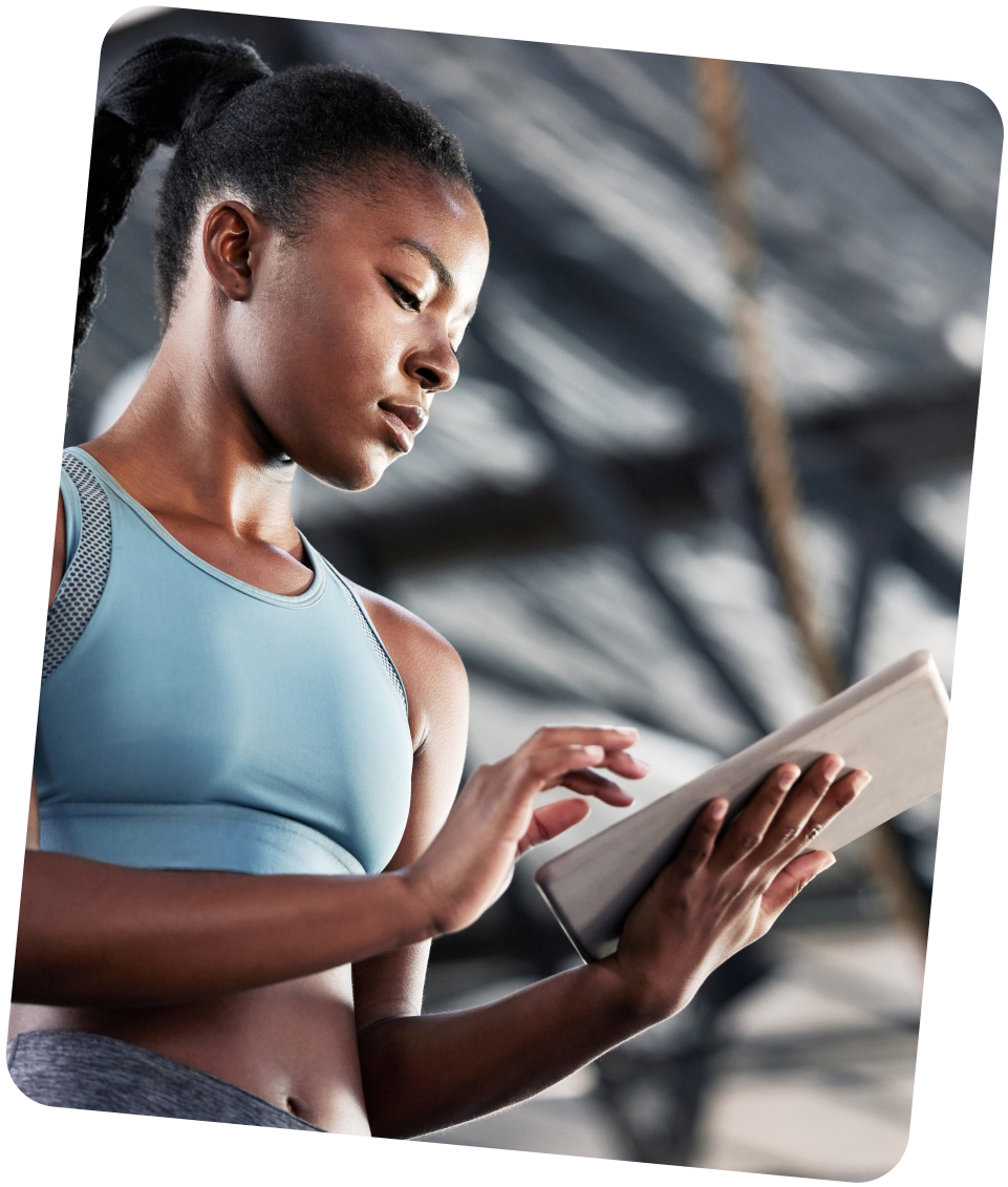Woman in a sports bra using a tablet in a gym