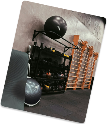 Gym corner with a dumbbell rack, medicine balls and a wooden ladder wall