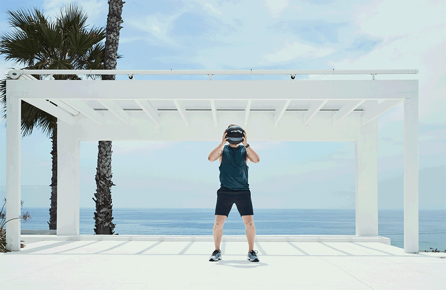 Athlete pressing a medicine ball overhead in an outdoor training session by the ocean.
