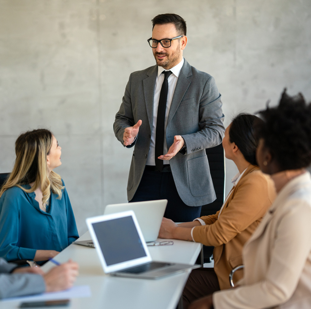 A coach presenting to two leaders in a conference room
