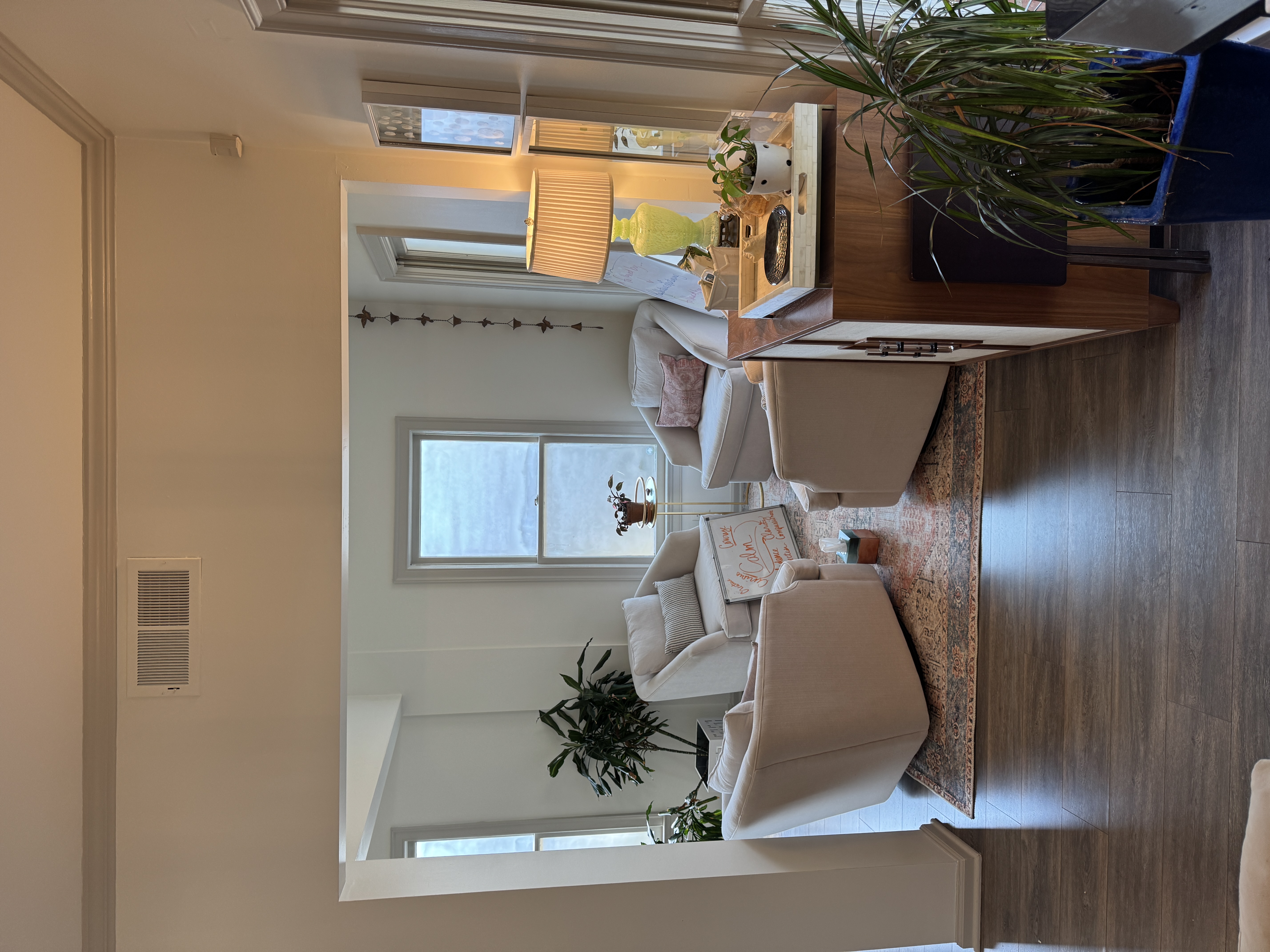 Bright, airy counseling waiting room with white swivel chairs, plants and an ornate rug at the Germantown office