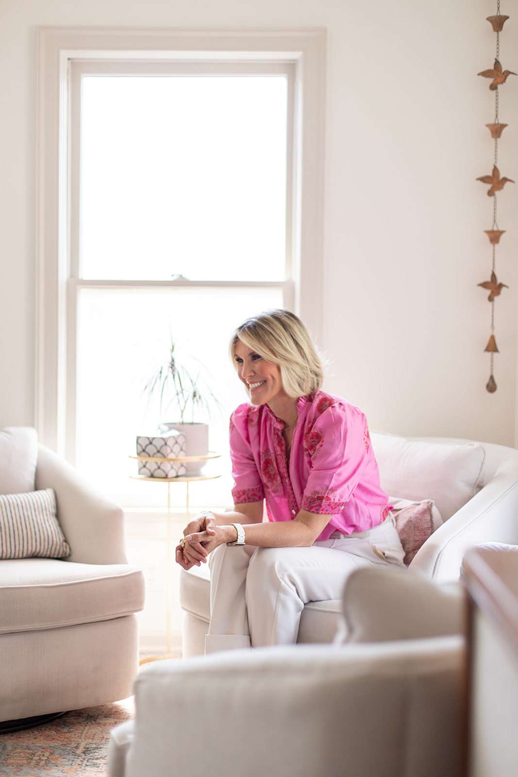 Michelle Johns sitting in a white chair smiling and leaning forward